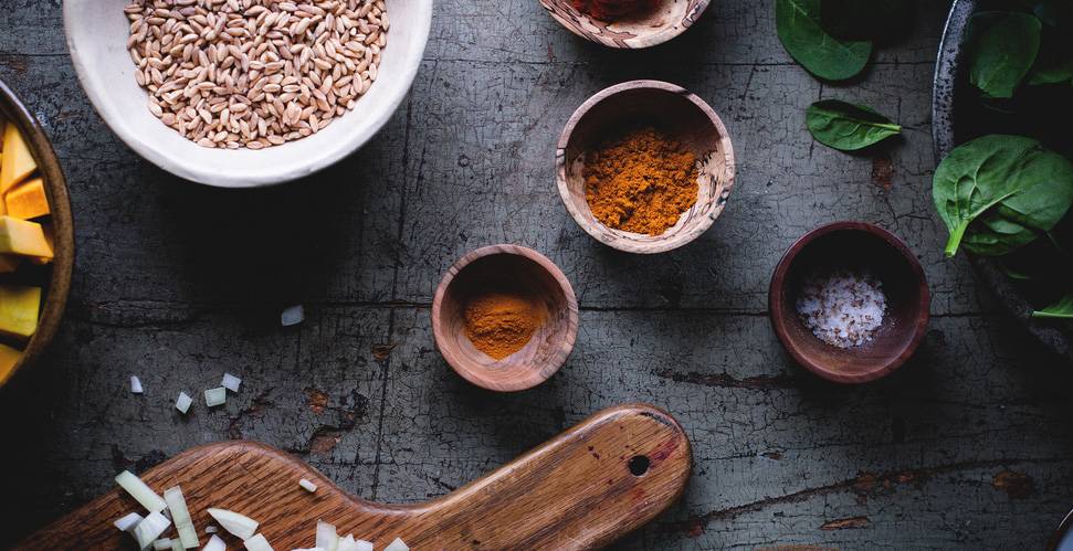 Spices, grains, and greens on table.